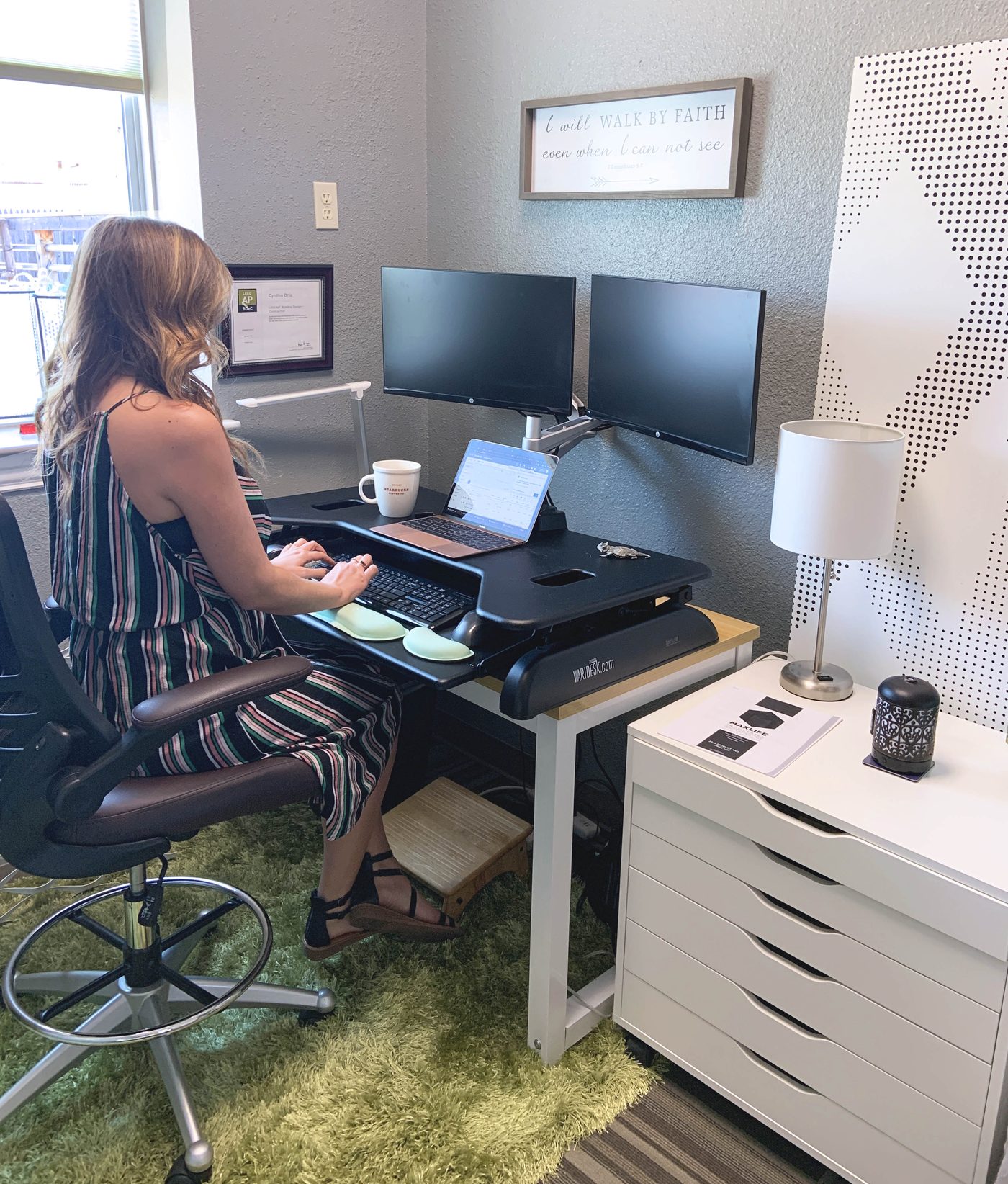 Member working at a sit-stand desk in a window office at Ensemble